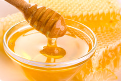 bowl of honey surrounded by honeycombs