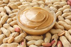bowl of peanut butter surrounded by un-shelled peanuts