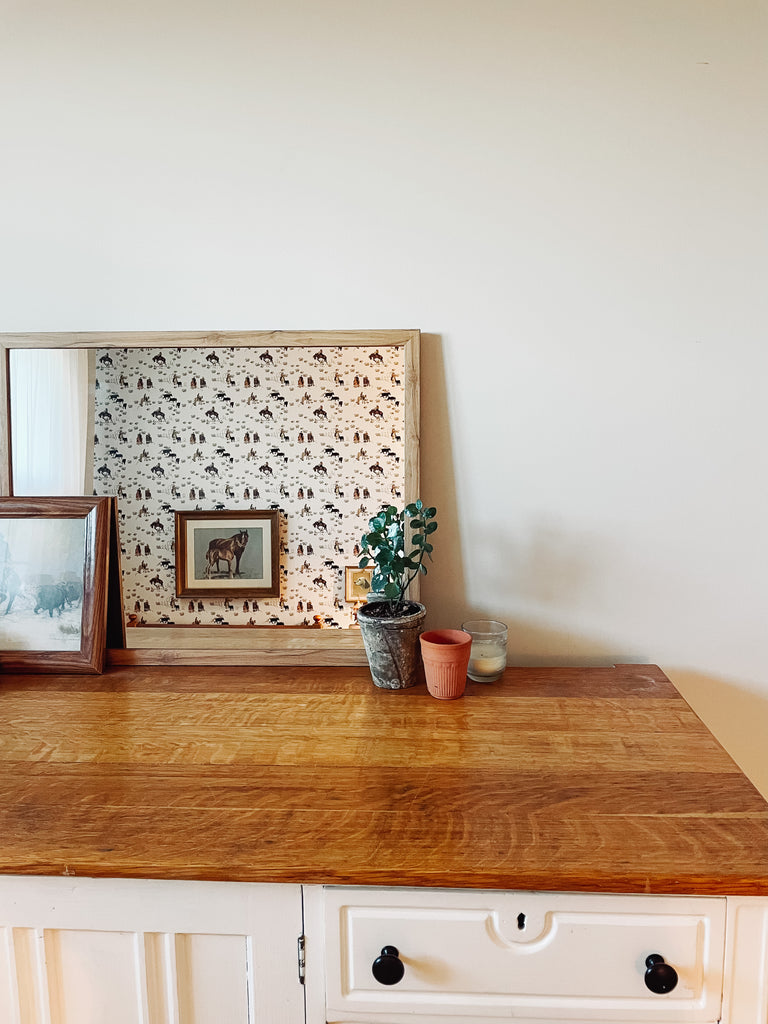 Cowboy wallpaper in a mirror reflecting western room decor