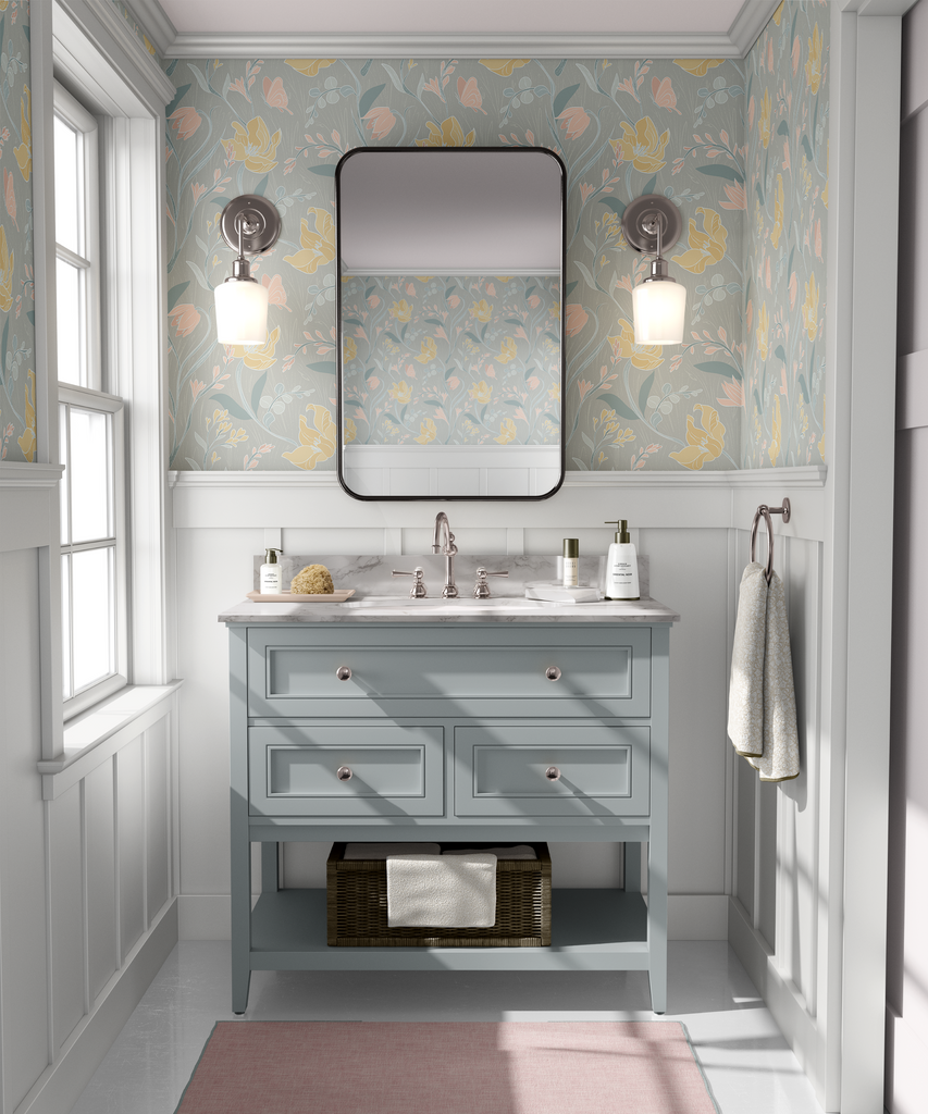 A bathroom with pastel floral wallpaper, featuring a vanity with a marble top and a large mirror flanked by wall sconces.