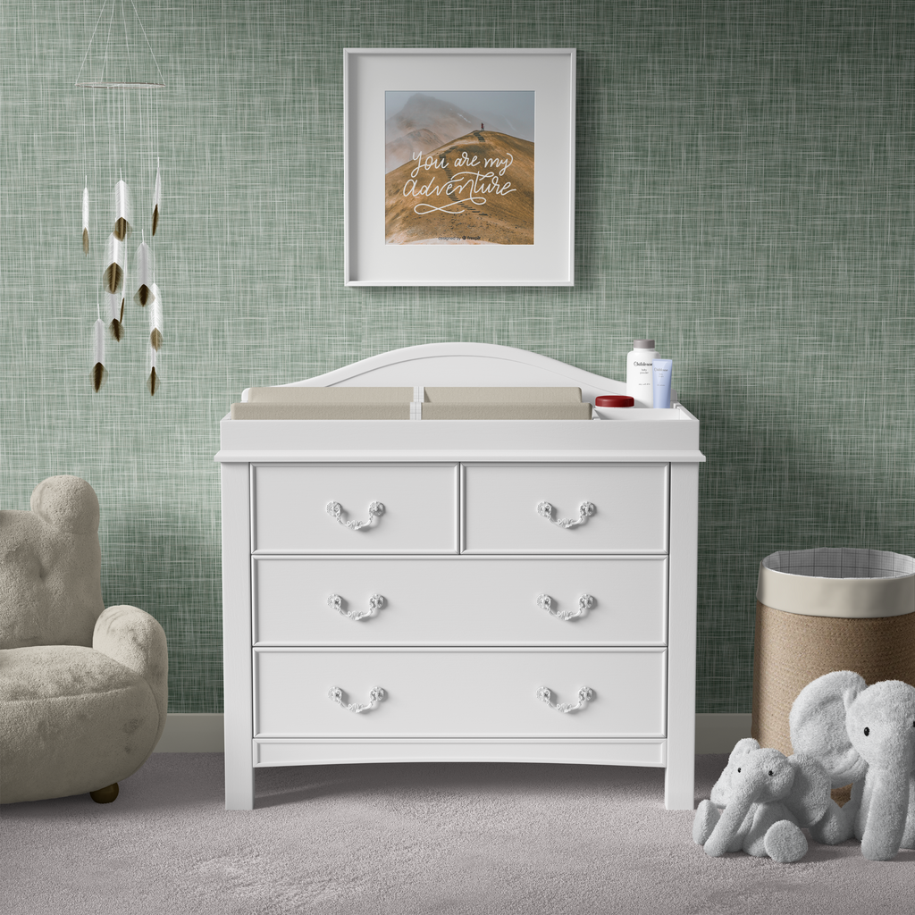 A serene nursery with sage green grasscloth wallpaper, creating a calm and elegant environment for a white dresser and plush toys.