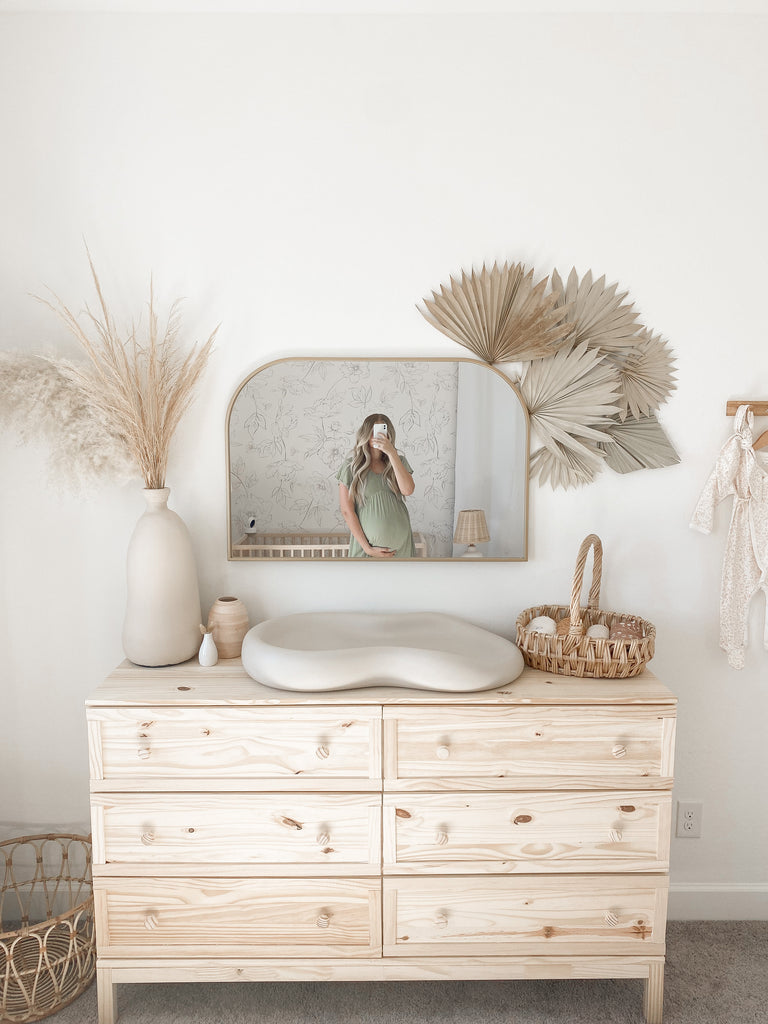 Bohemian nursery with natural wood dresser, pampas grass and palm leaves