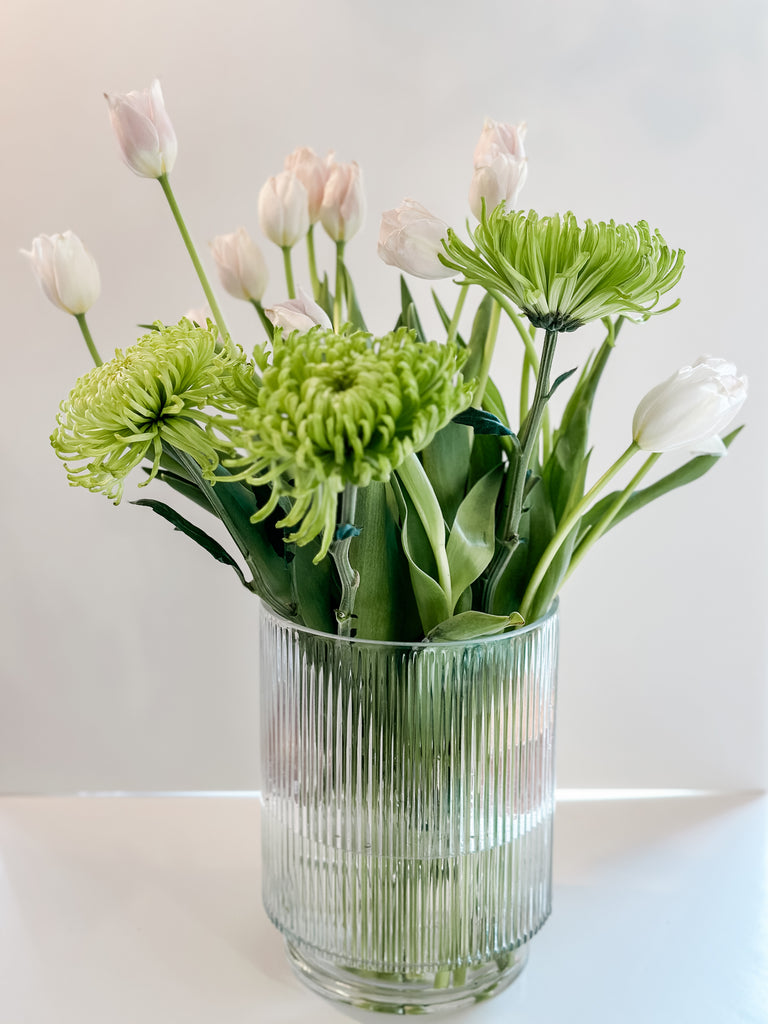 Chic white tulips paired with lush green spider mums in a glass vase, an affordable DIY approach to upscale flower shop styling