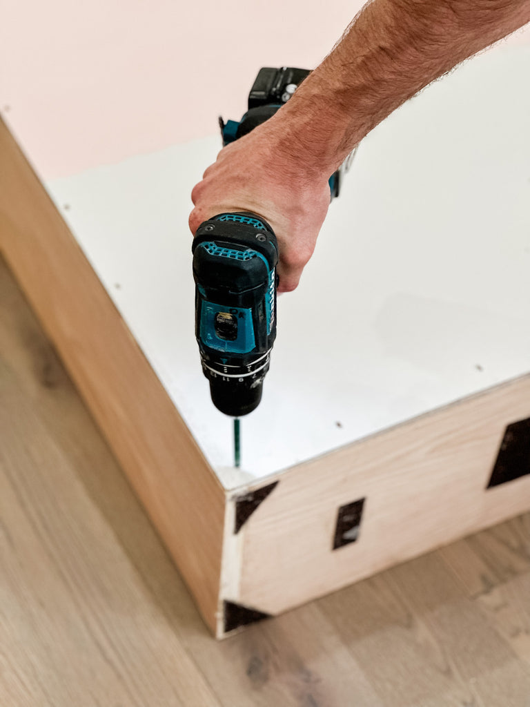 Screwing the back of a custom dollhouse with floral design onto a vintage dollhouse