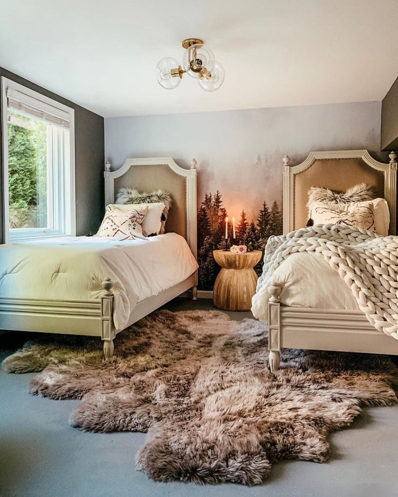 Cozy guest bedroom with faux fur rug, mountain and forest wallpaper and two beds.