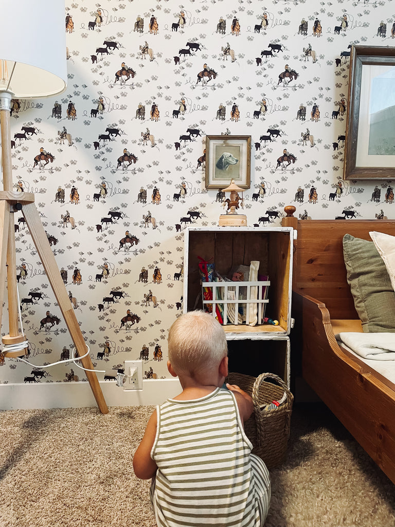 Little boy sitting in his western themed cowboy bedroom