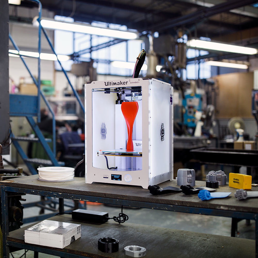 Ultimaker 2 Extended+ on an industrial workbench printing a tall red propeller