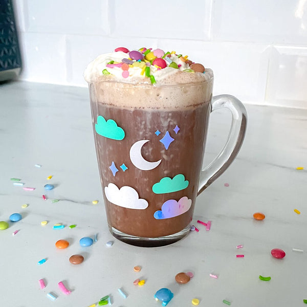 Sprinkle Club - A cute glass mug with stars, clouds and a moon design on with hot chocolate and whipped cream in it