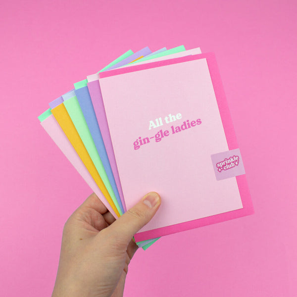 Sprinkle Club - Someone holding a collection of pink and girly Christmas cards with sassy quotes