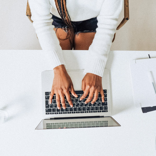 Sprinkle Club - A woman sitting at a desk using her laptop to research what hashtags her competitors are using