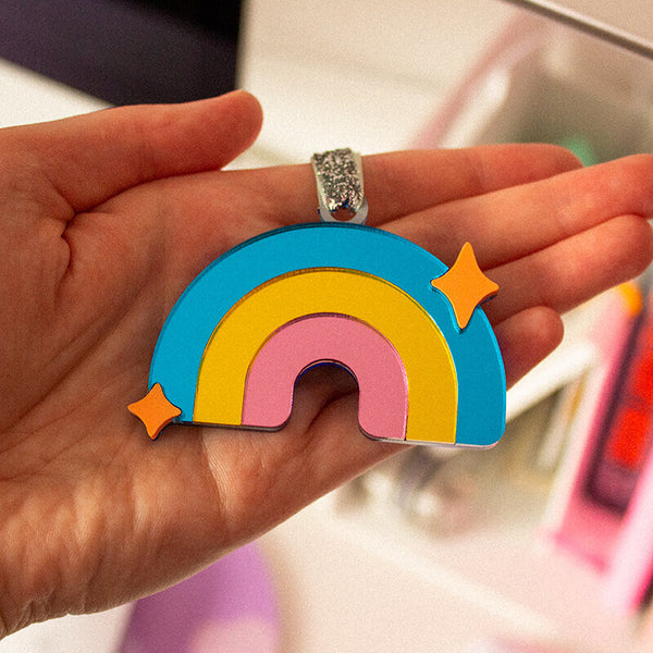 Sprinkle Club - Someone holding a small mirrored rainbow window hanging ornament with a silver sparkly string