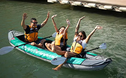 A family of 3 having fun while paddling in their 3 person kayak