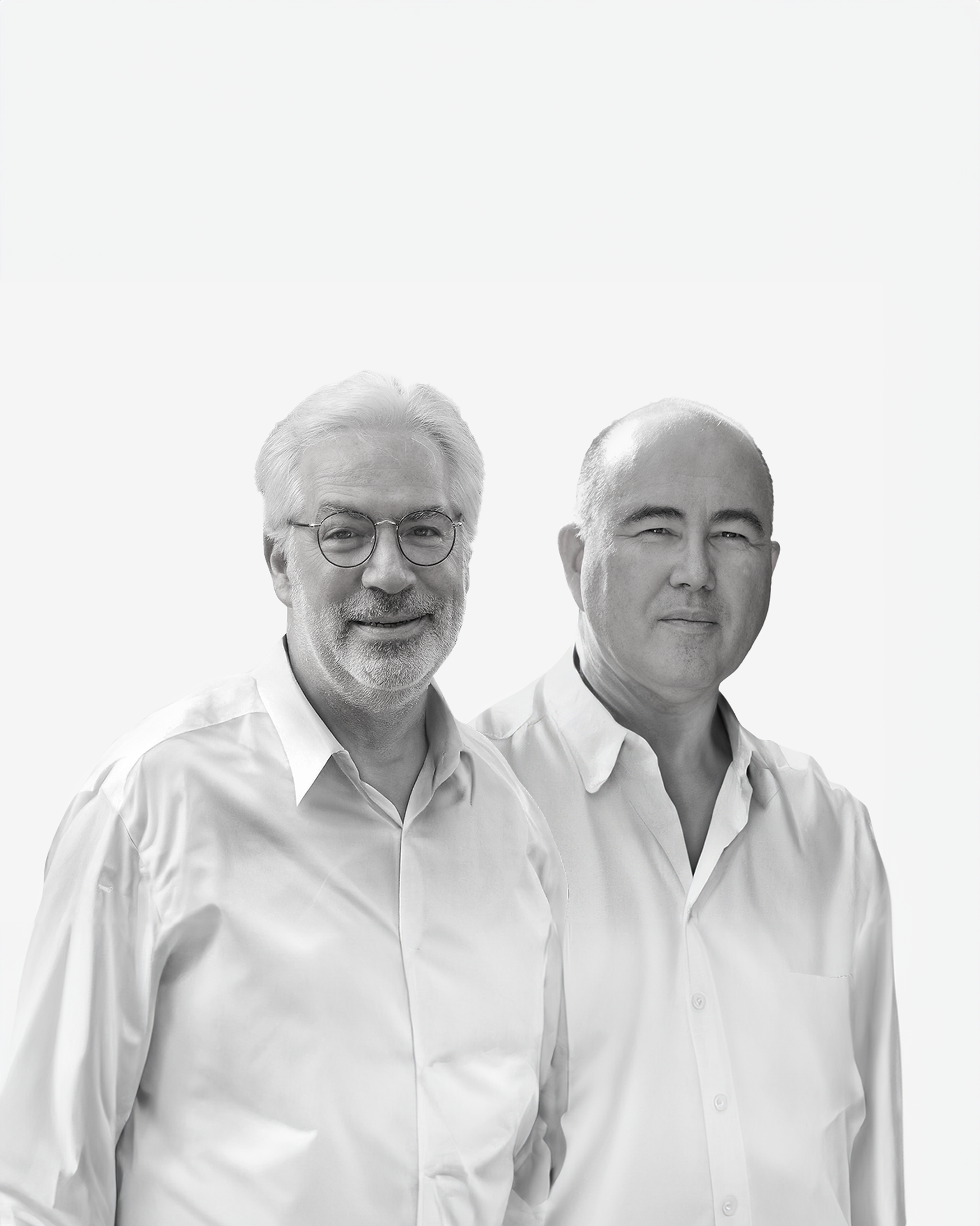 Black and white portrait of two smiling men in white shirts against a white background.