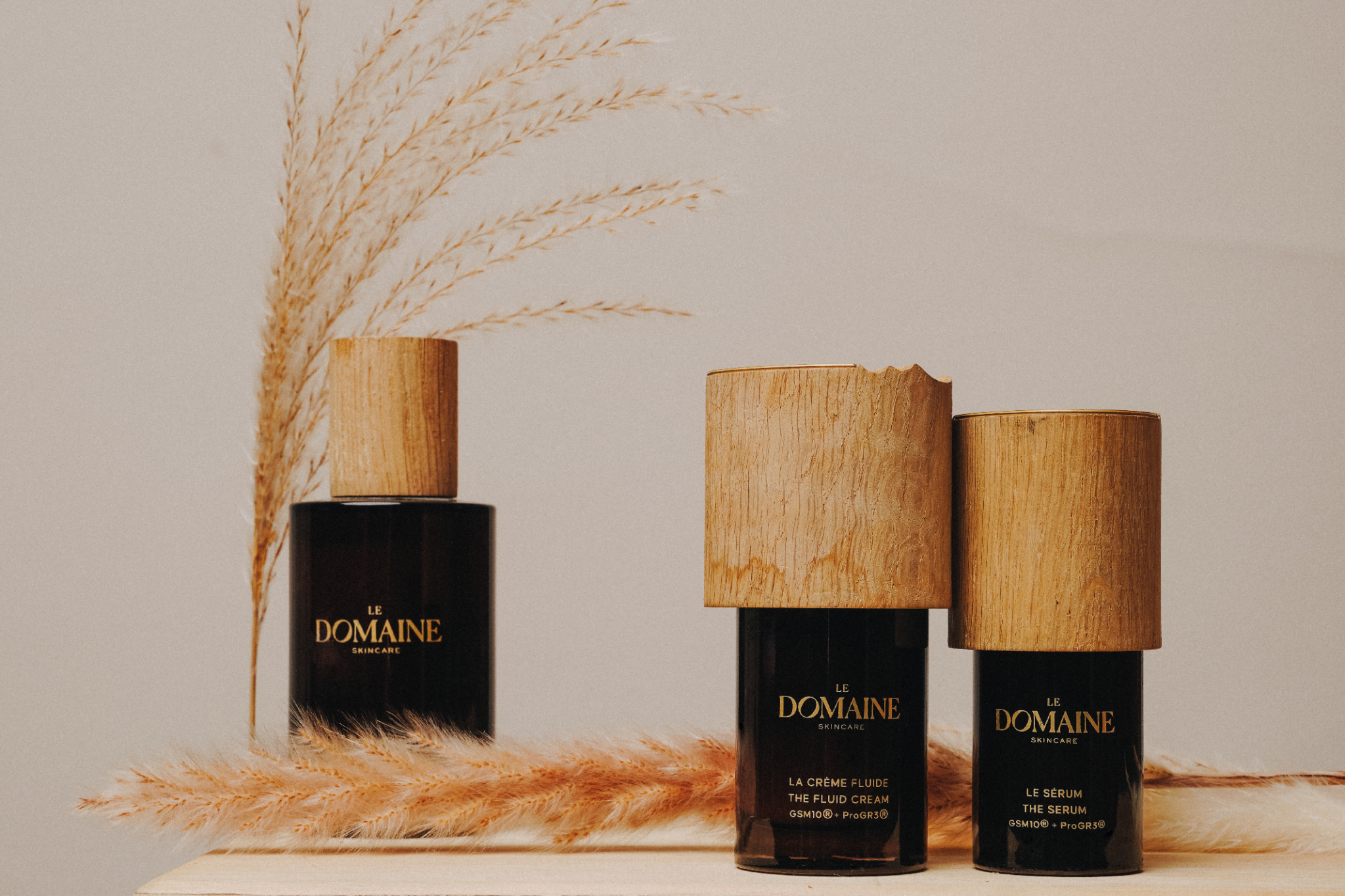 Skincare products with wooden caps and decorative plants in the background.