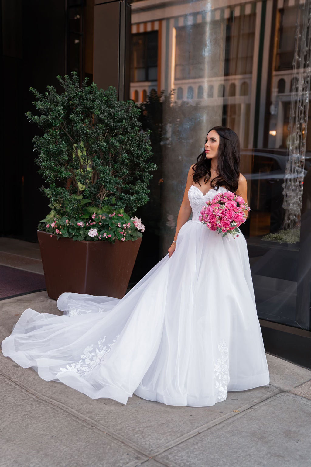 Bride Mariana in a strapless ball gown wedding dress by Krismil Bridal, holding a pink bouquet in New York City.