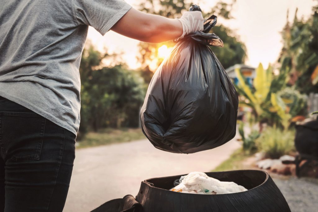 Woma holding garbage bag 