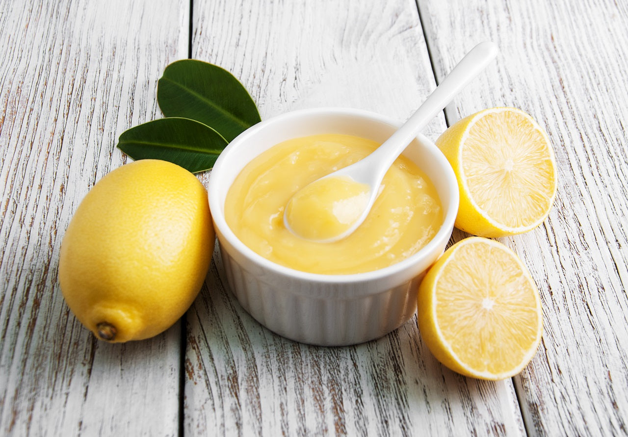 Lemon mousse in a ceramic cup with cut lemons beside it