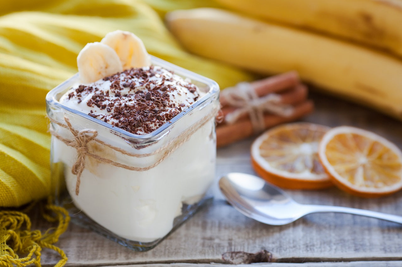 Banana pudding in a glass jar with its ingredients around it