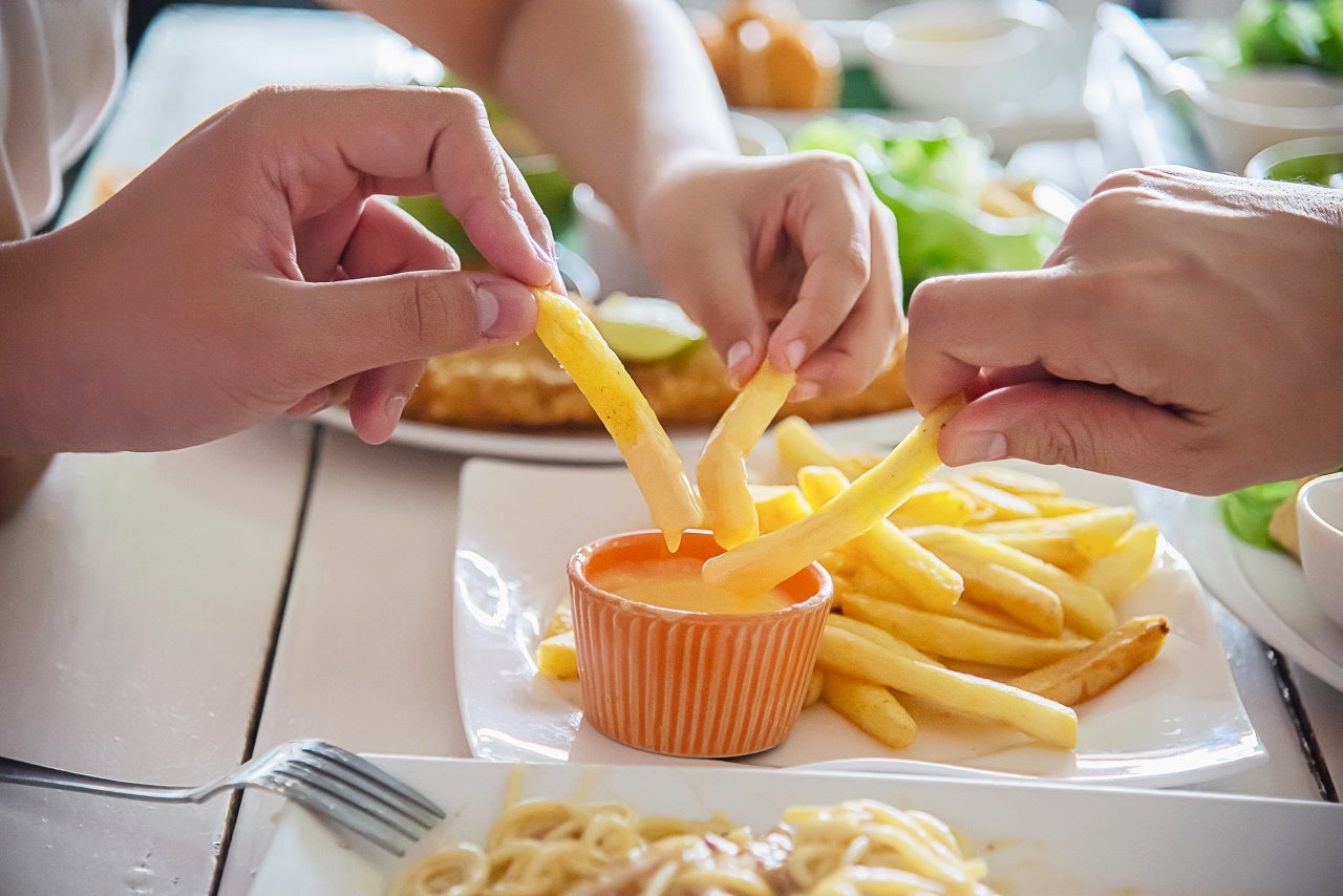 A group of people eating a plate of french fries