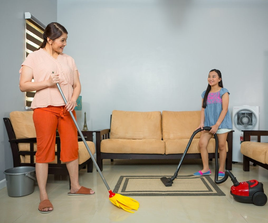 A mother and daughter cleaning their living room