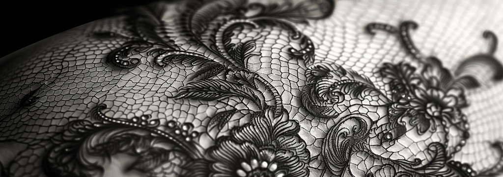 A lace tattoo adorns the upper back. The tattoo's fine lines and shading create a realistic lace effect, beautifully complementing the back's natural shape.