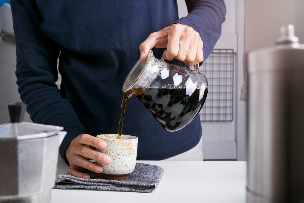 a man pouring black coffee into a cup