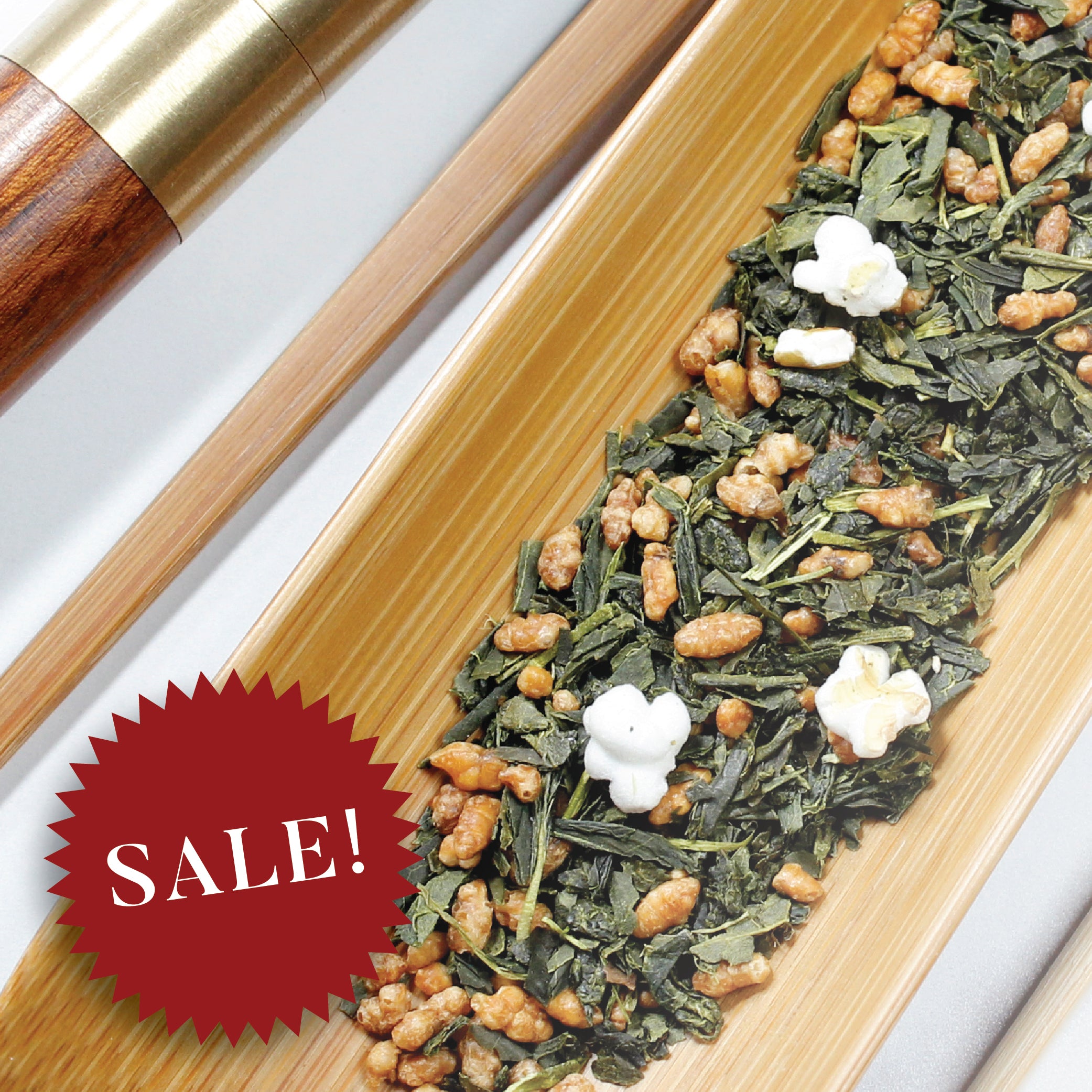 A bamboo scoop holds Genmai Cha blended green tea. A 15% off sale badge rests over the image.
