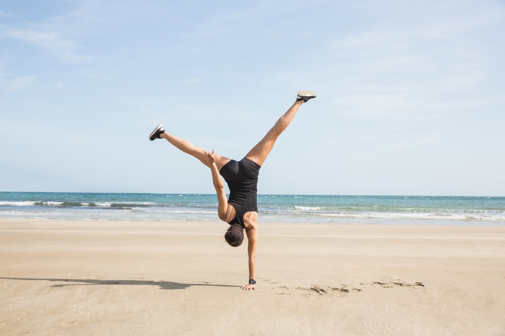 woman on a beach doing a handstand