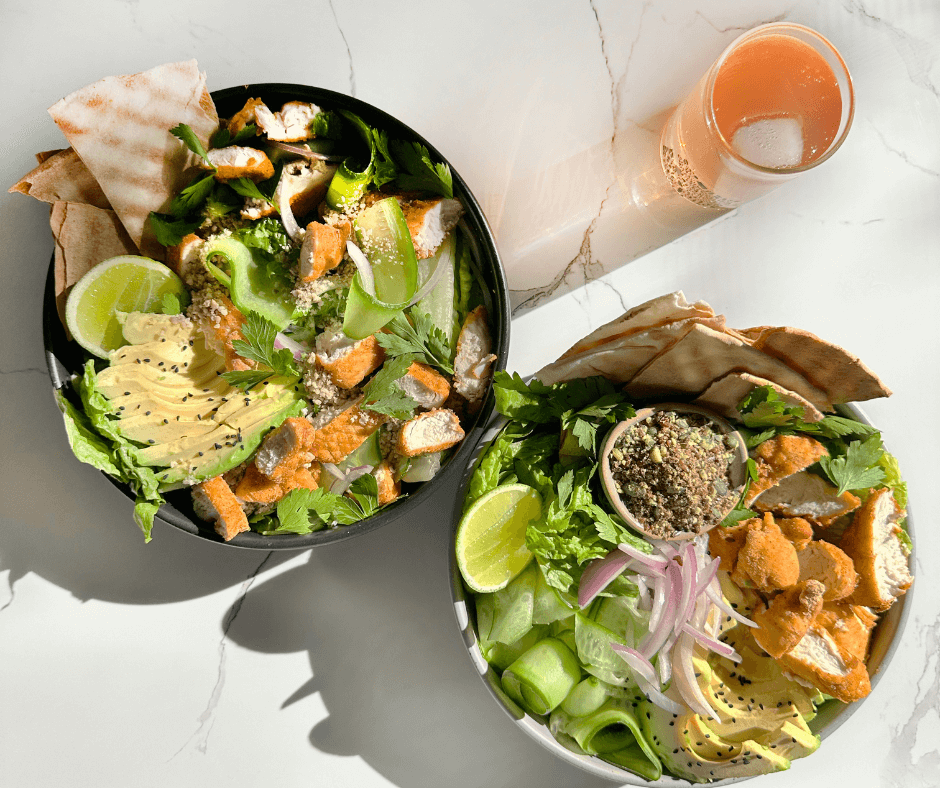 Chicken Pita Nourish Bowl recipe 2 bowls on kitchen bench with salad seed cycle and chicken, with glass of sparkling water and ice.
