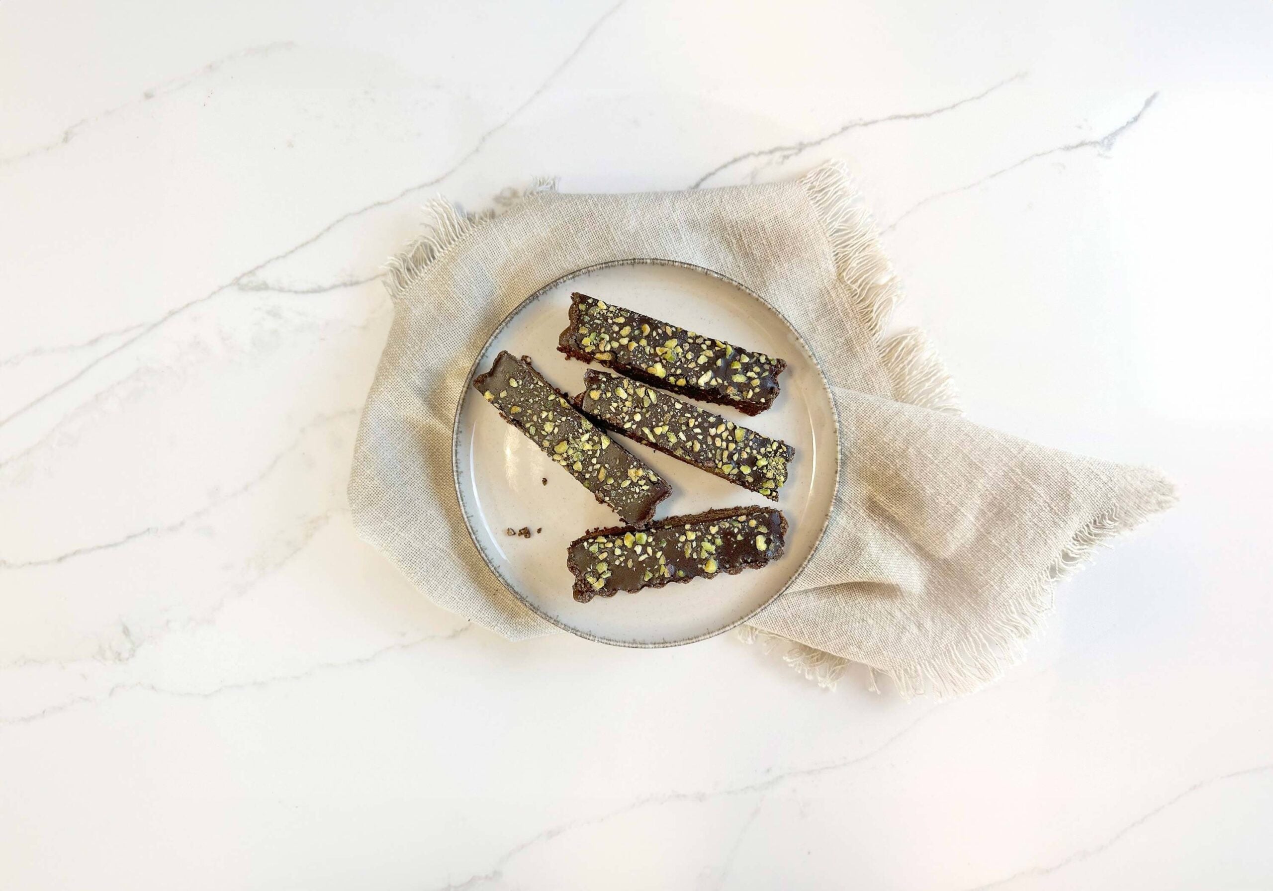 Seed cycling phase 2 chocolate bars cut up on a round plate with tea towel underneath on kitchen bench