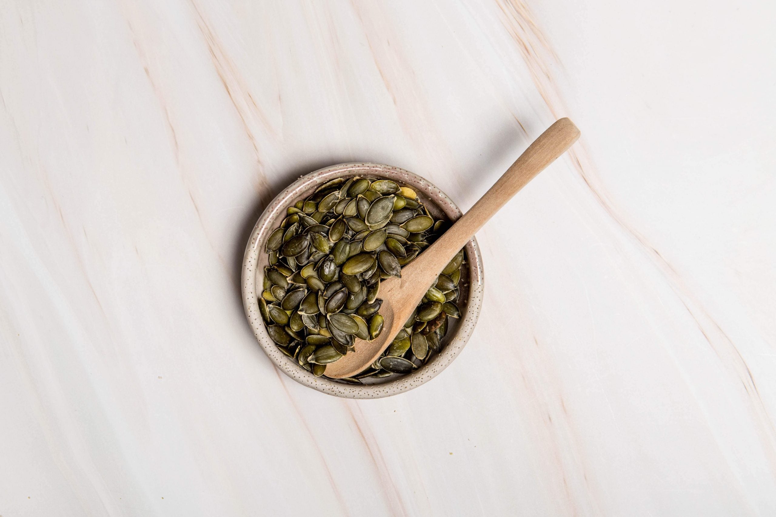 A bowl of pumpkin seeds sitting on a kitchen bench with a wooden spoon in the bowl. What is seed cycling?