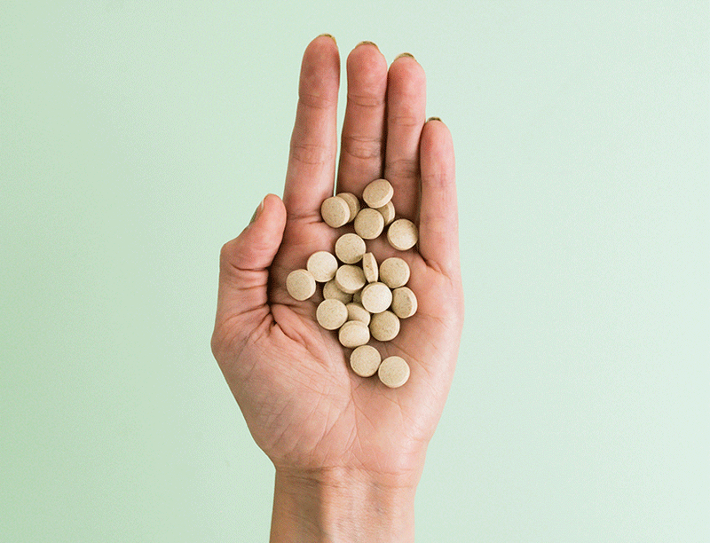 Woman's Hand Holding Apple Cider Vinegar Tablets