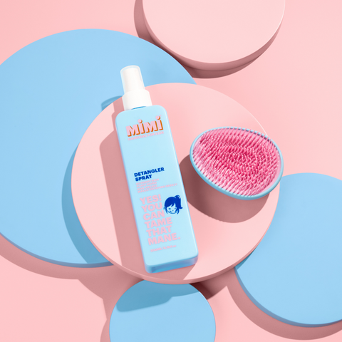 Picture of a bottle of detangler spray and a detangler brush from Mimi Haircare for kids. Both are coloured blue and pink and super cute.