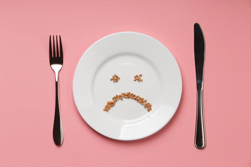 dish jn a pink table with sad smile formed by seeds fork and knife on a side