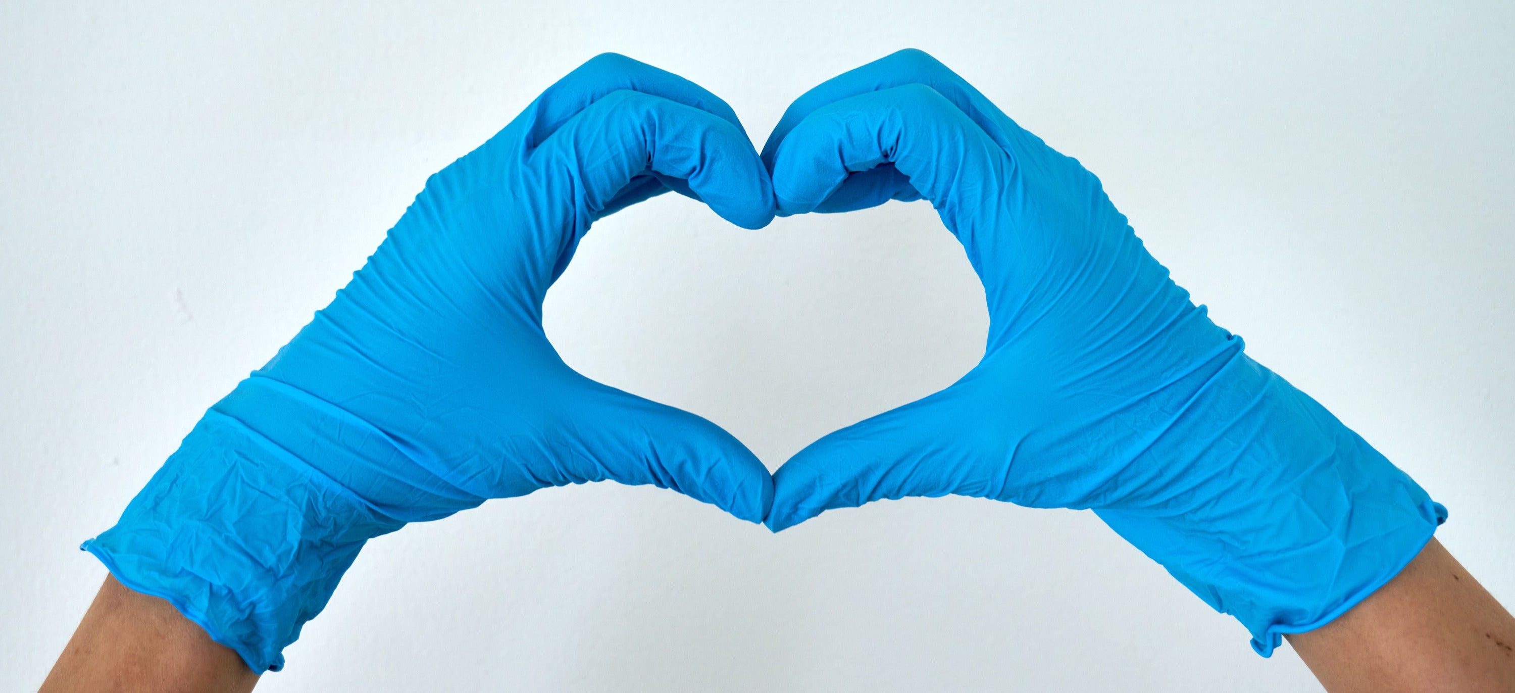 Hands in blue medical glowes form a heart shape