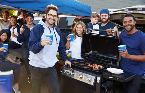 Happy group of friends grilling at a high school football game tailgate
