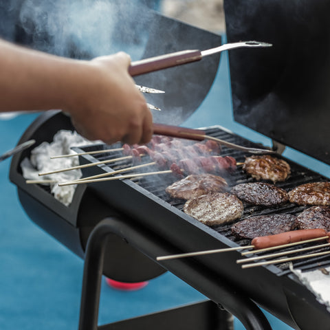 hand with spatula over a hot bbq grill with burgers