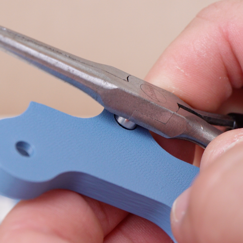 inserting the magnet into the hinge with the side of needle nose pliers