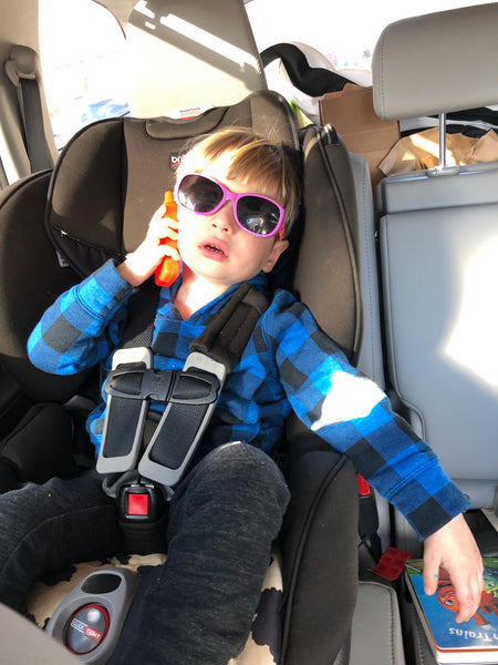 Emmett wearing sunglasses and on his phone in his carseat