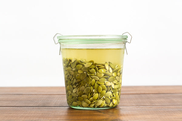 Jar of pumpkin seeds soaking in water. Soaking seeds helps our bodies absorb their nutrients. 