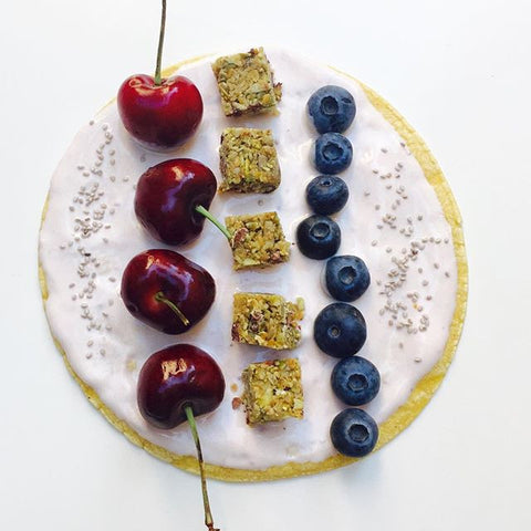 Tostada spread with yogurt, cherries, blueberries,  chunks of dark chocolate sea salt seed bar, and chia seeds. Gluten-free, nut-free option for kids!