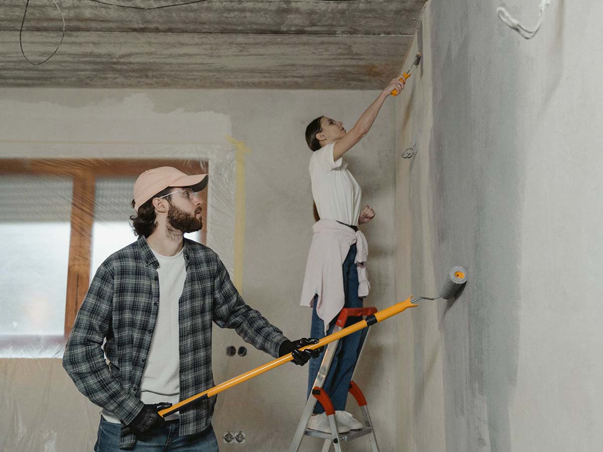 A man and woman repaint their home's interior, immersed in a DIY renovation project.