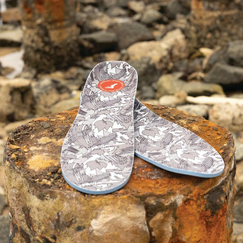 Image of FP Insoles Kingfoam Orthotics Insoles in their white camo print, set criss-crossed on a stump outdoors.