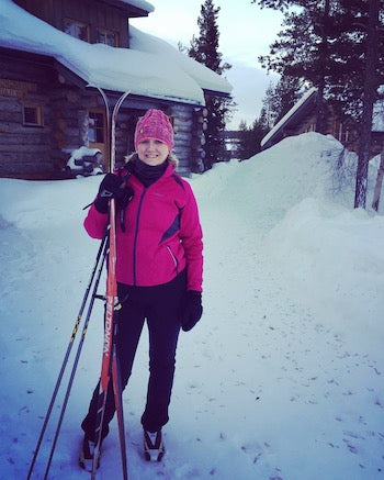 Me in a pink skiing outfit holding my skis in Lapland, Finland
