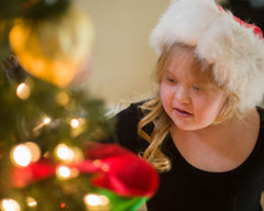 Down syndrome child in a Christmas hat and looking at the warm Christmas tree lights.