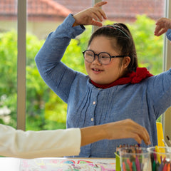 Disabled child flapping her hands as sitting at a table