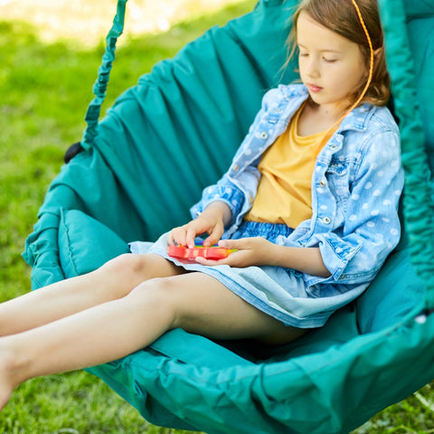 Child sitting on a swing playing with a fidget toy