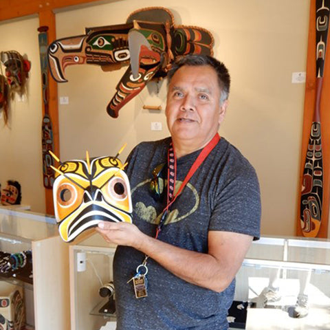 Indigenous artist Sandy Johnson holding carved bumble bee mask