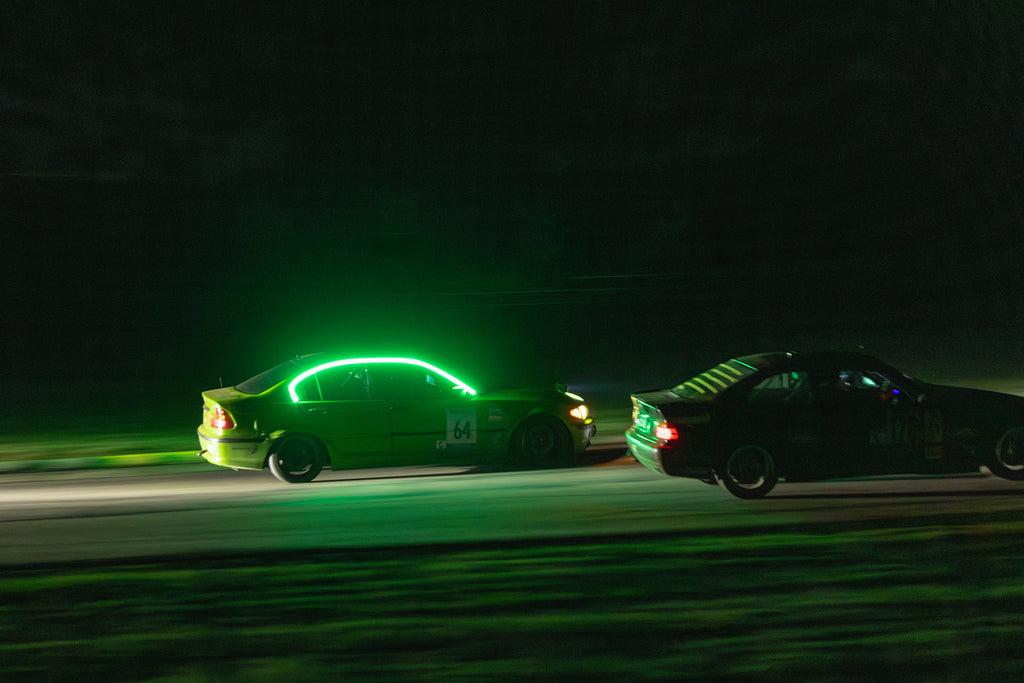 Two cars race at night at the Virginia International Raceway (VIR).