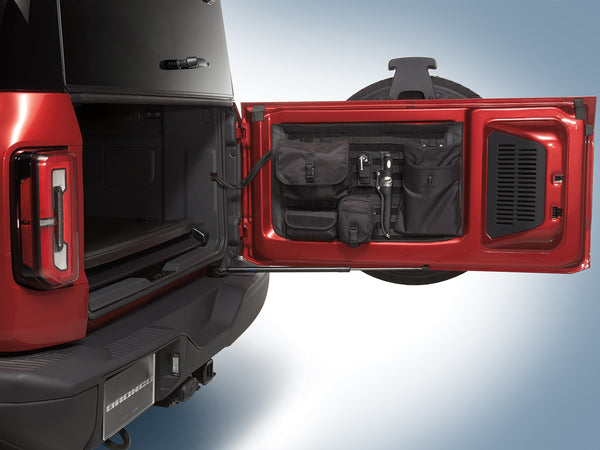 A red 2021-2023 Ford Bronco with MOLLE panel fixed to the swing gate with tools mounted.